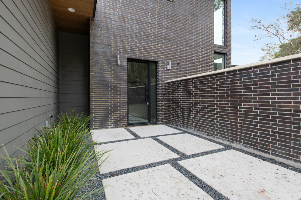 Mittelgroßes, Zweistöckiges Retro Einfamilienhaus mit Backsteinfassade, grauer Fassadenfarbe, Flachdach und Schindeldach in Austin