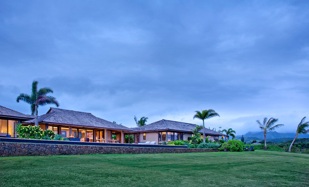 Beige world-inspired bungalow house exterior in Hawaii with a hip roof.