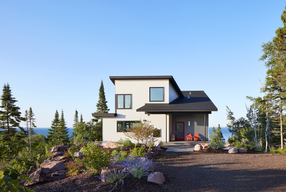 Cette photo montre une façade de maison blanche bord de mer à un étage avec un toit en appentis, un toit en shingle et un revêtement mixte.