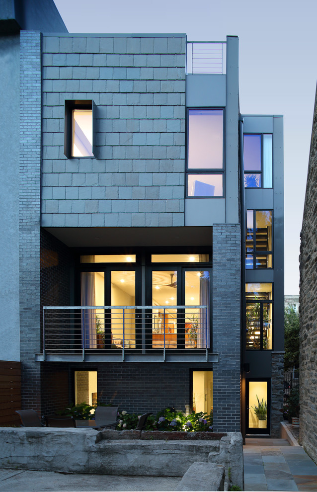 This is an example of a large and gey modern terraced house in Philadelphia with three floors, stone cladding, a flat roof and a mixed material roof.