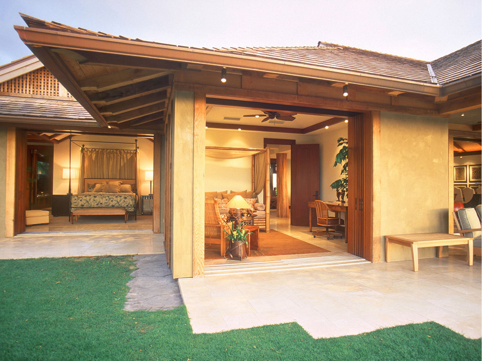 Ejemplo de fachada de casa beige tropical con revestimiento de estuco, tejado a cuatro aguas y tejado de teja de barro