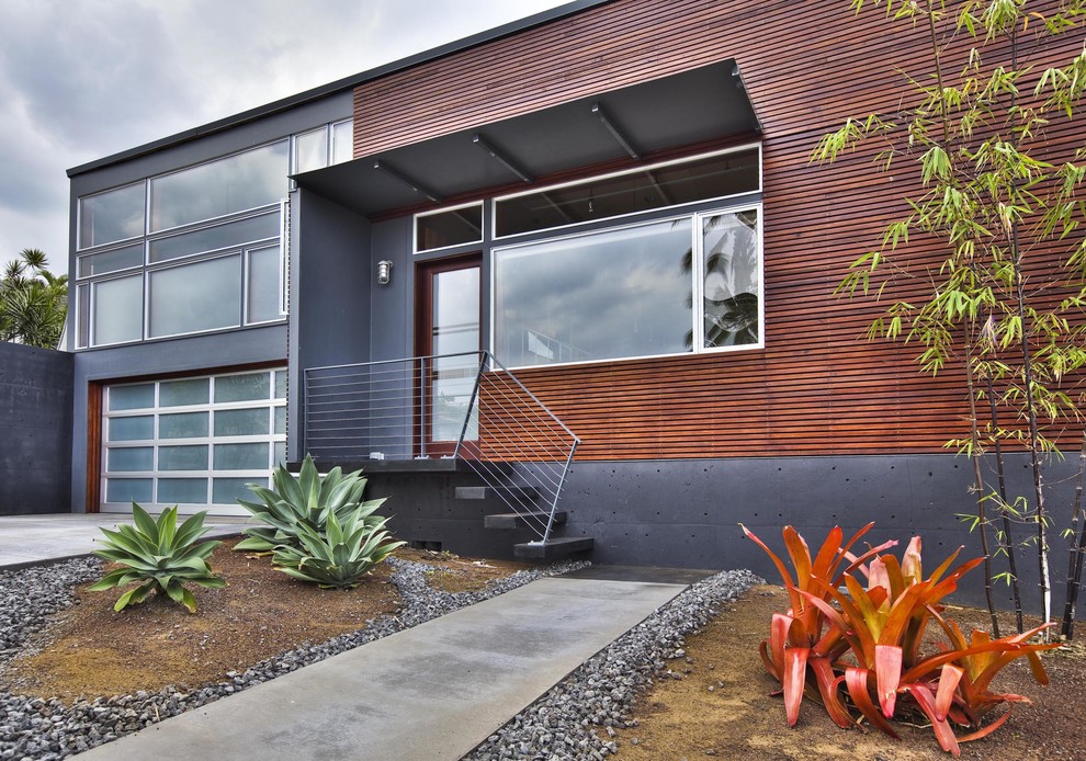 Cette image montre une façade de maison design avec un revêtement mixte.