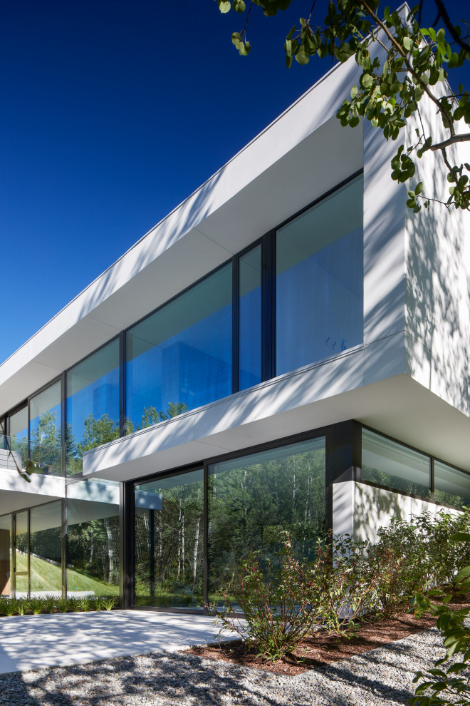 Inspiration för stora moderna vita hus, med två våningar, stuckatur och platt tak