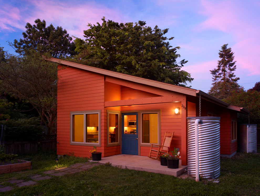 Exempel på ett modernt oranget hus, med allt i ett plan och pulpettak