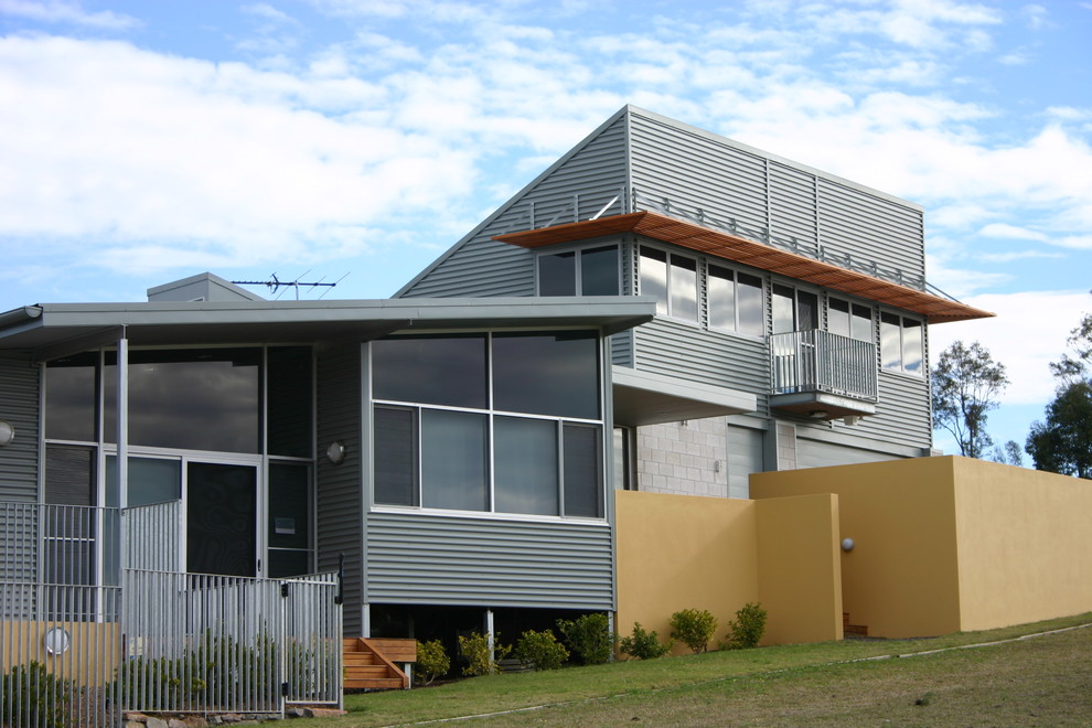 Ejemplo de fachada de casa gris industrial de tamaño medio a niveles con revestimiento de metal