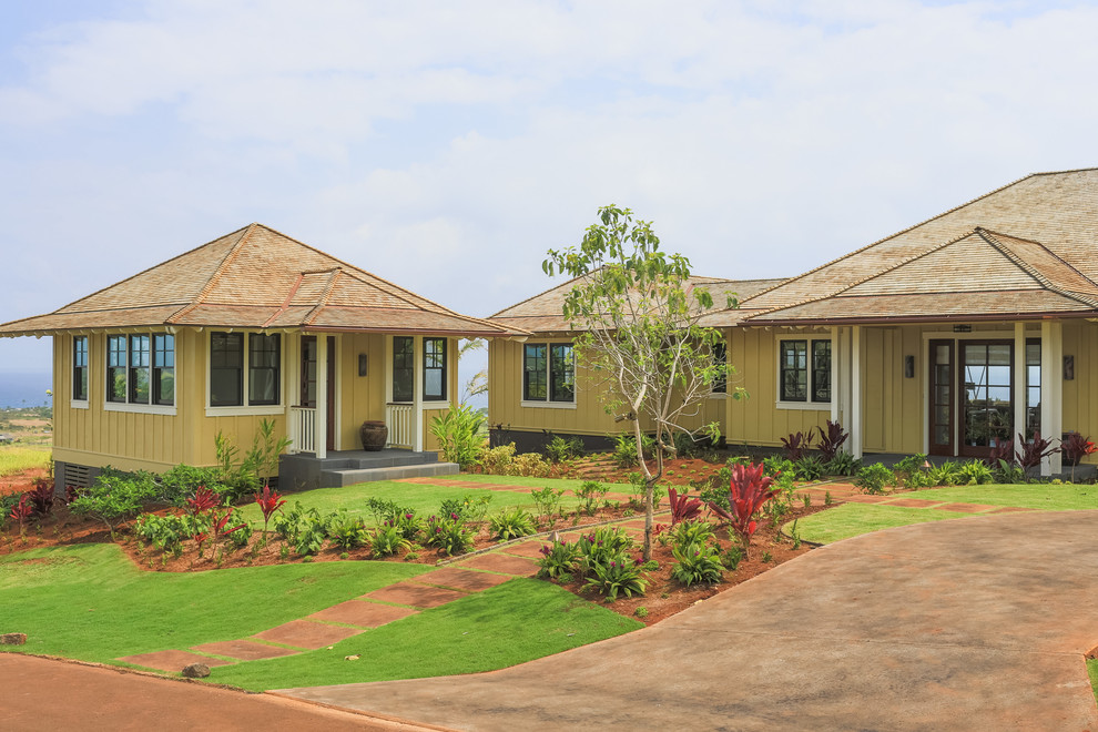 Example of an island style yellow one-story exterior home design in Hawaii with a hip roof