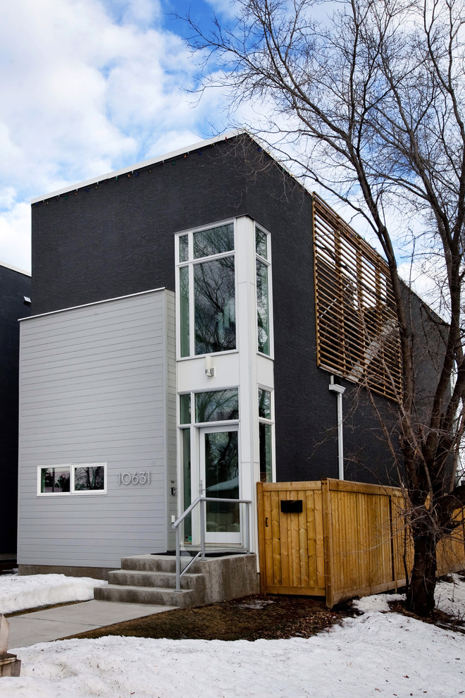 Inspiration pour une façade de maison grise minimaliste en stuc à un étage.
