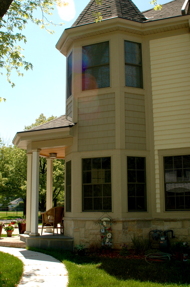 Exemple d'une façade de maison beige chic en panneau de béton fibré à deux étages et plus et de taille moyenne avec un toit à deux pans et un toit en shingle.