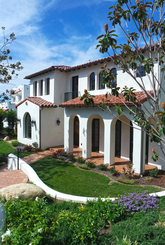 На фото: большой, двухэтажный, белый дом в средиземноморском стиле с облицовкой из цементной штукатурки