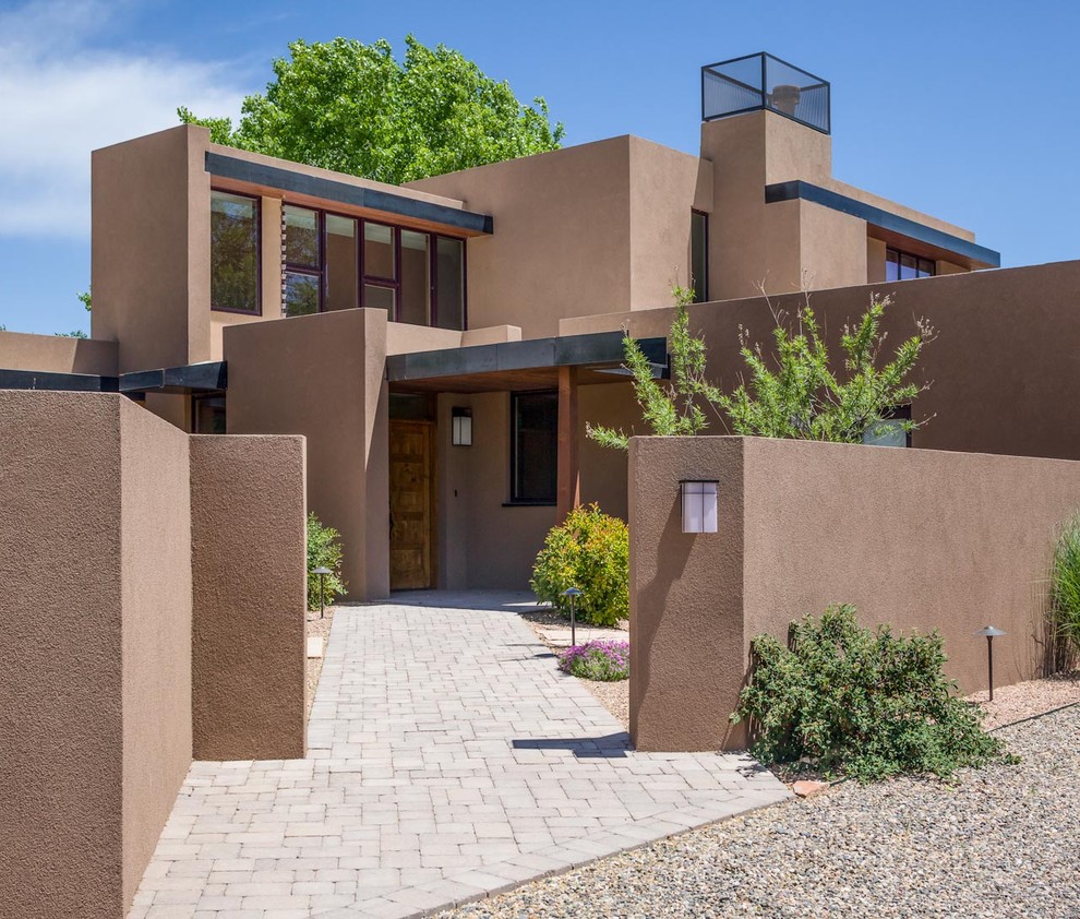Large and brown two floor render detached house in Albuquerque with a flat roof and a metal roof.