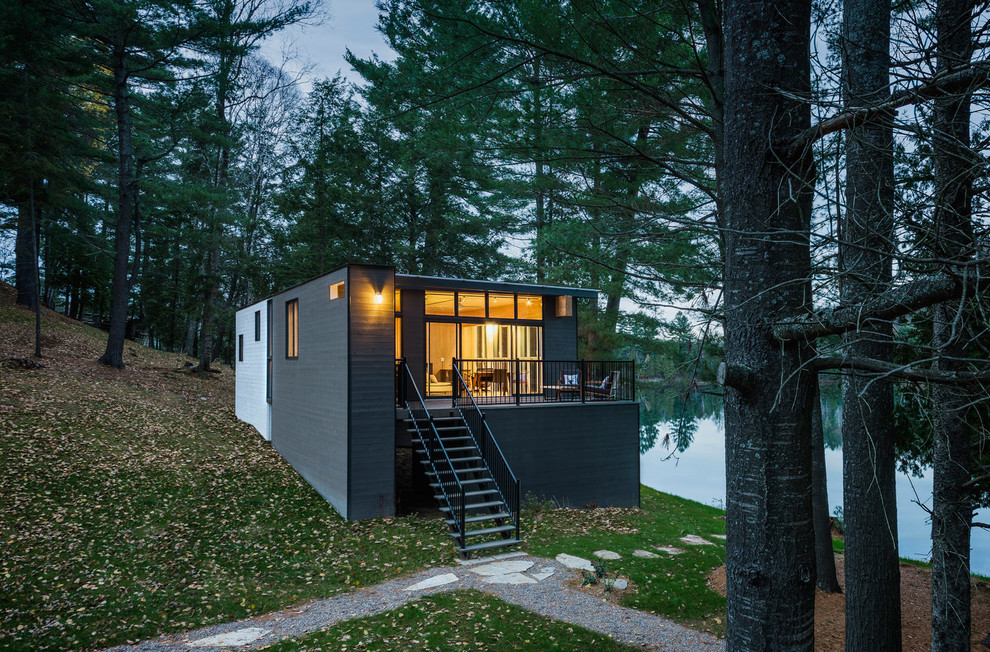 Immagine della facciata di una casa nera contemporanea con rivestimento in legno, tetto piano e abbinamento di colori