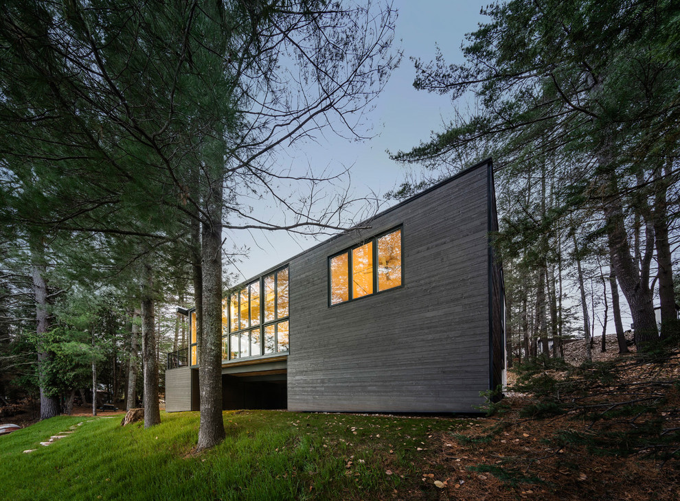 This is an example of a black contemporary house exterior in Ottawa with a flat roof and wood cladding.