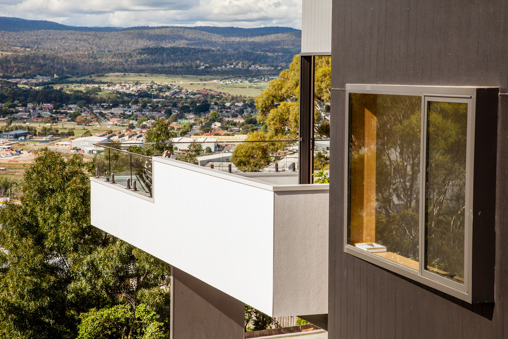 This is an example of a medium sized and gey contemporary two floor house exterior in Hobart with concrete fibreboard cladding and a flat roof.