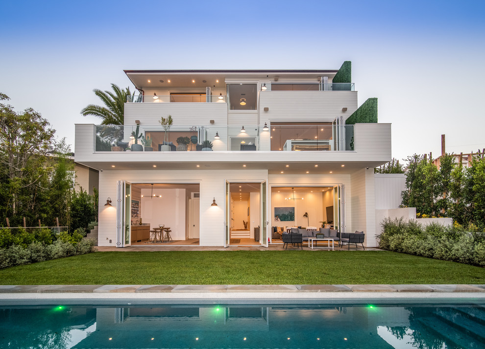 Large beach style white three-story wood house exterior photo in Los Angeles with a shingle roof
