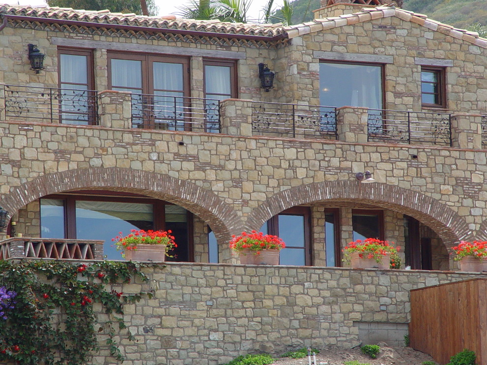 Idées déco pour une façade de maison beige méditerranéenne en pierre de taille moyenne et à un étage avec un toit plat.