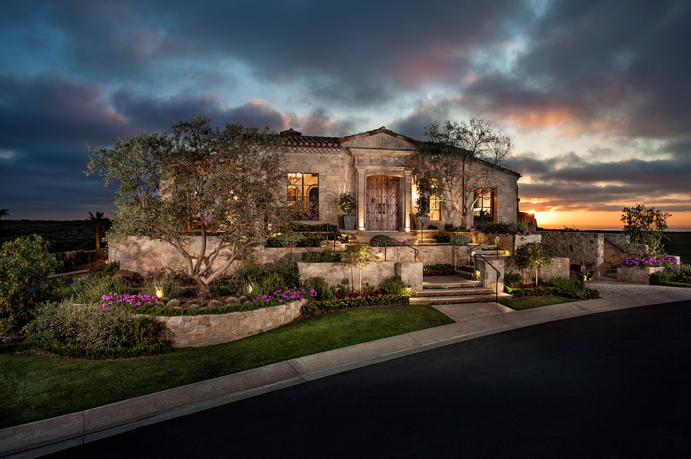 Großes, Dreistöckiges Mediterranes Haus mit Steinfassade und grauer Fassadenfarbe in Orange County