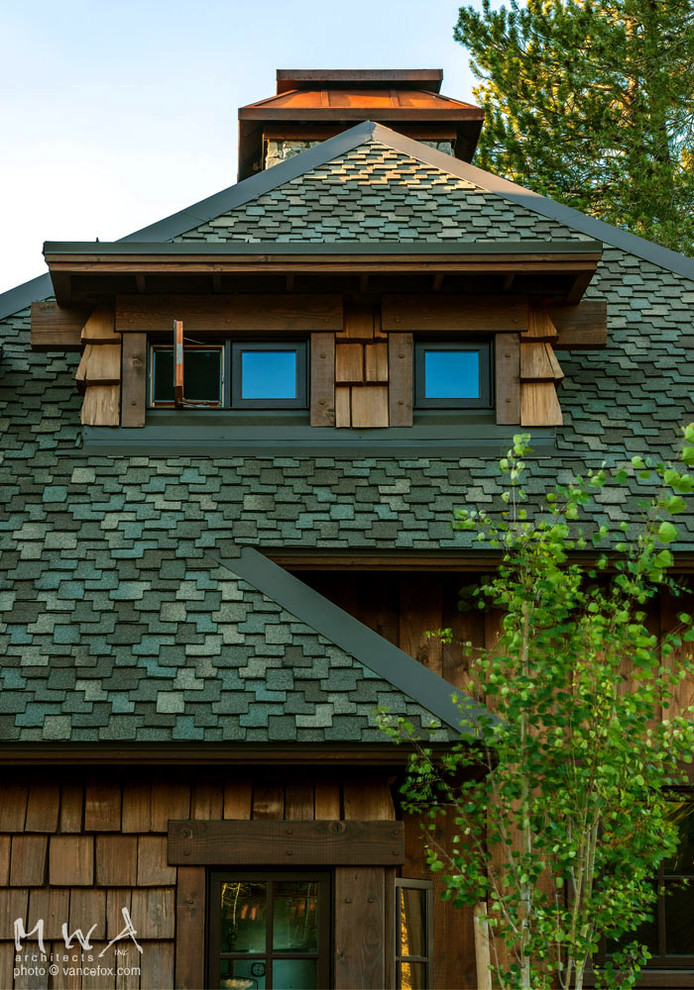 Foto de fachada marrón rústica grande de dos plantas con revestimiento de madera y tejado a cuatro aguas