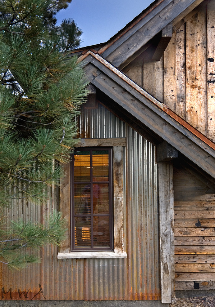 Imagen de fachada de casa marrón rústica de dos plantas con revestimientos combinados y tejado a dos aguas