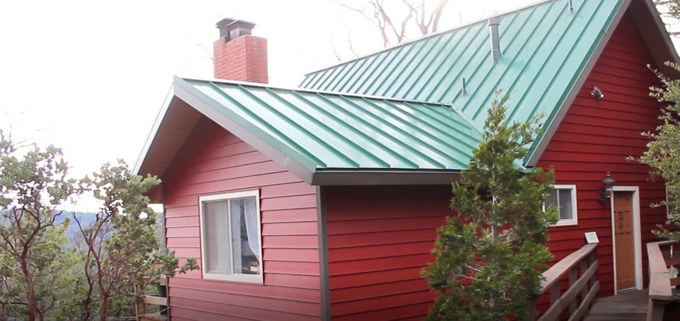 Idée de décoration pour une grande façade de maison rouge chalet à un étage avec un revêtement en vinyle et un toit à deux pans.