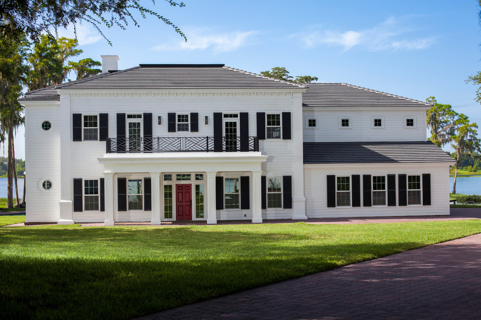 Photo of a large and white traditional two floor house exterior in Orlando with wood cladding and a hip roof.