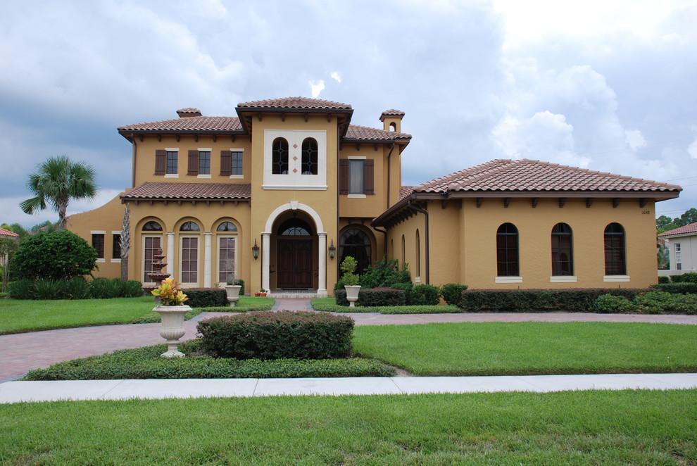 Example of a huge tuscan yellow two-story stucco gable roof design in Orlando