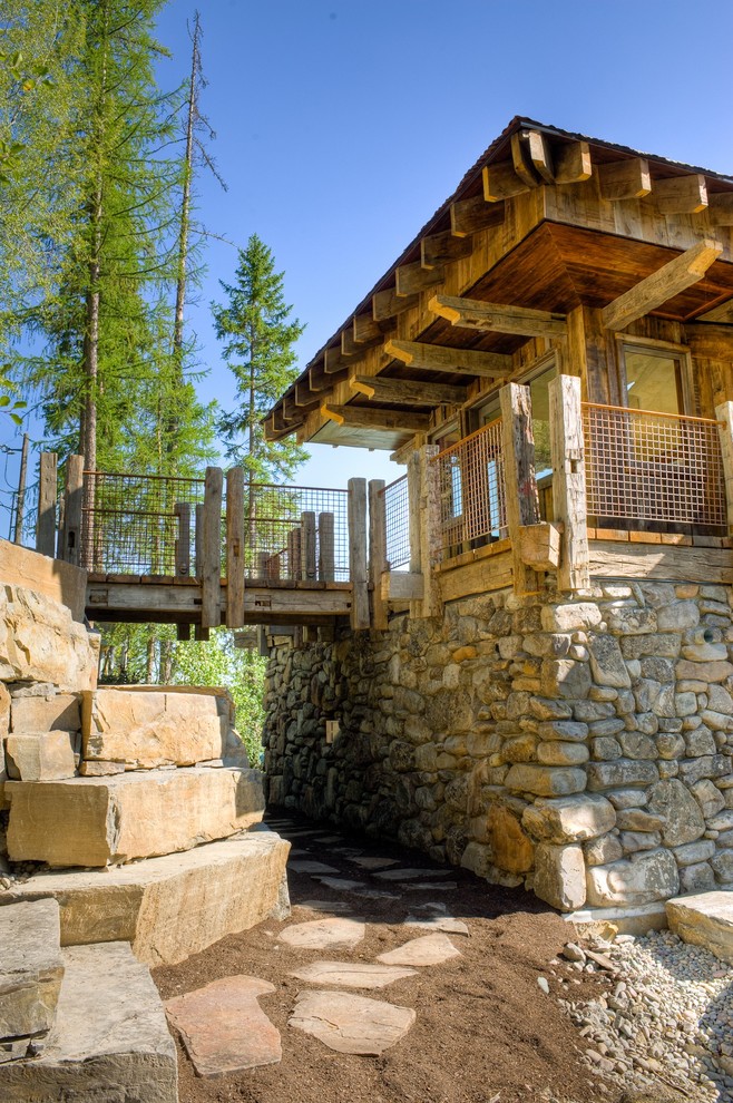 Design ideas for a rustic house exterior in Other with stone cladding.