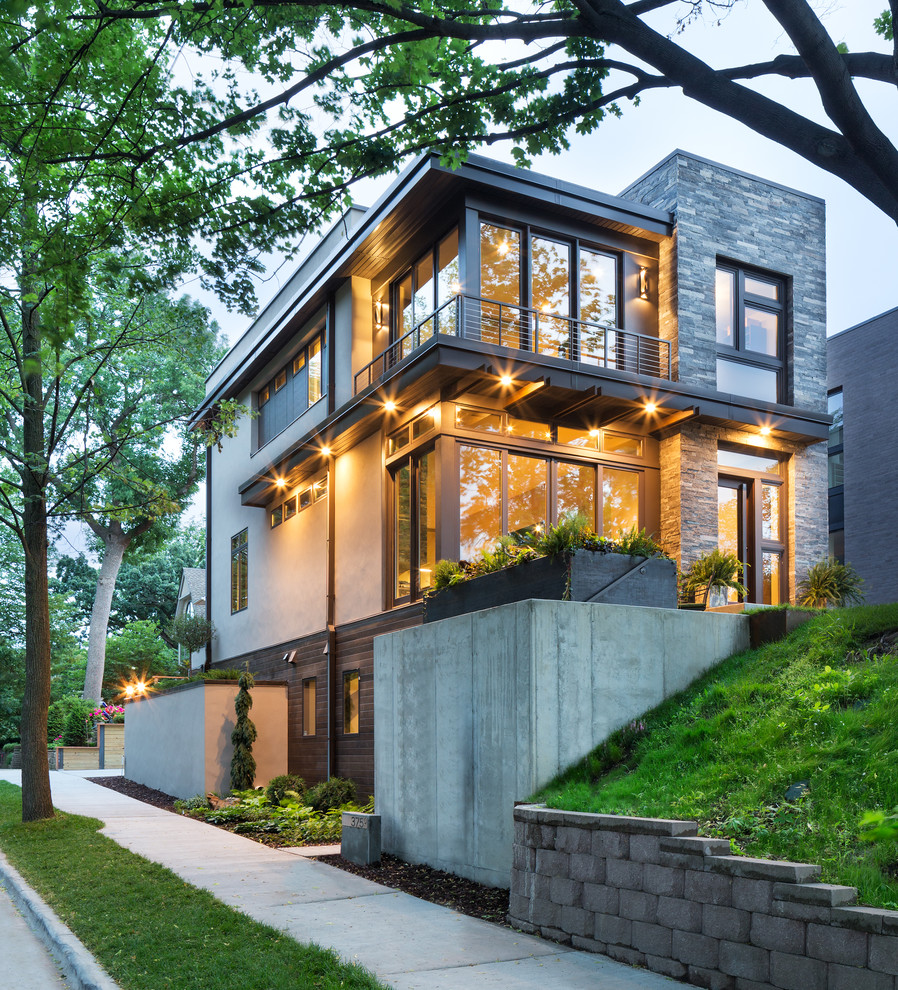 Cette photo montre une petite façade de maison grise moderne à un étage avec un revêtement mixte et un toit plat.