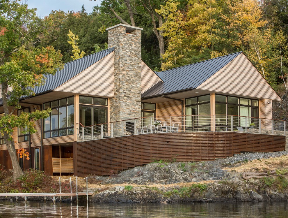 Diseño de fachada de casa beige actual grande de dos plantas con tejado a dos aguas, revestimientos combinados y tejado de metal