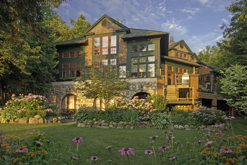 Foto della villa ampia verde american style a tre piani con rivestimento in legno, tetto a capanna e copertura a scandole