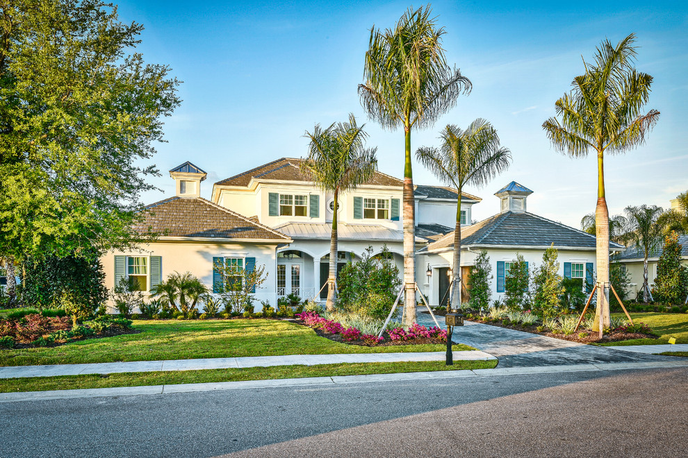 Large tropical white two-story stucco house exterior idea in Tampa