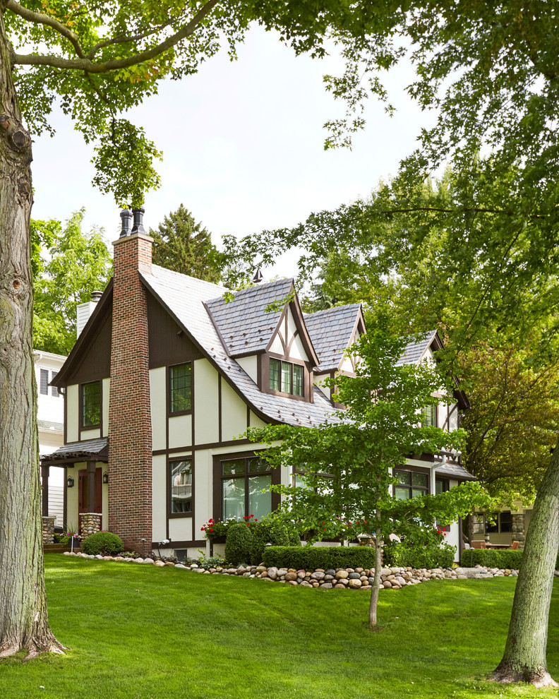 Cette photo montre une façade de maison blanche craftsman en stuc de taille moyenne et à un étage avec un toit à croupette et un toit en tuile.