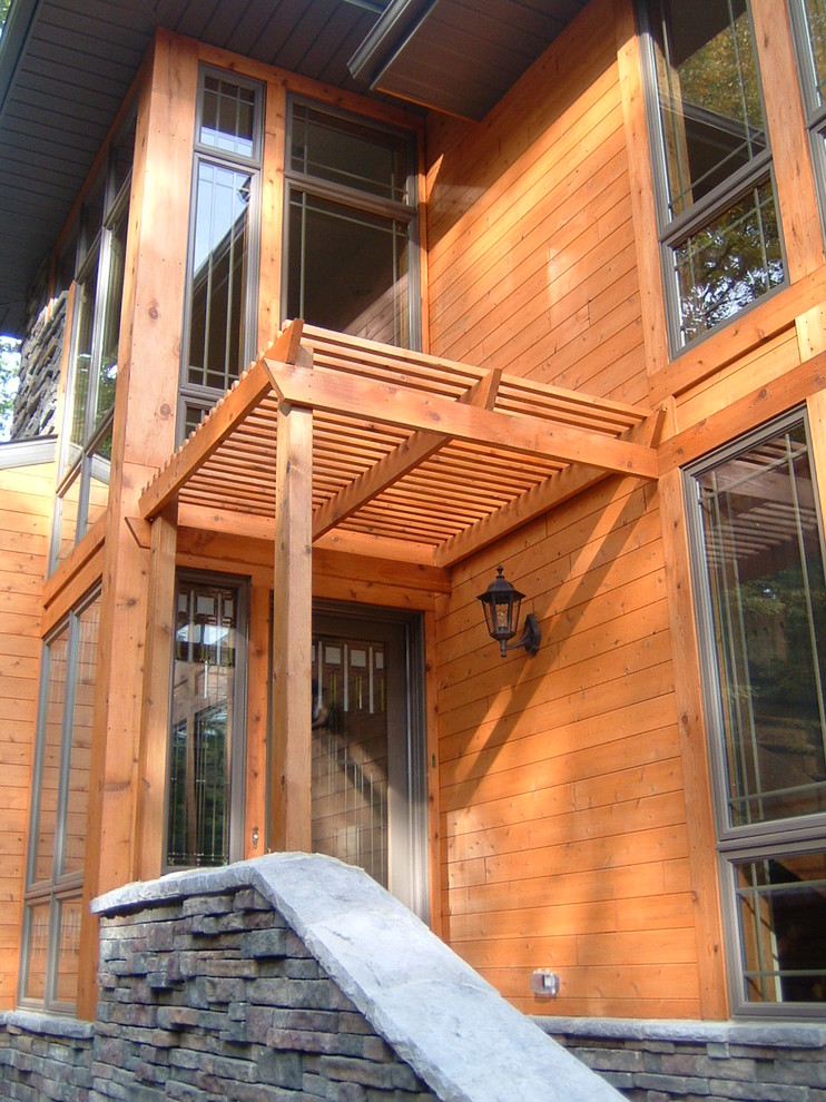 На фото: деревянный, красный дом среднего размера в стиле кантри с разными уровнями