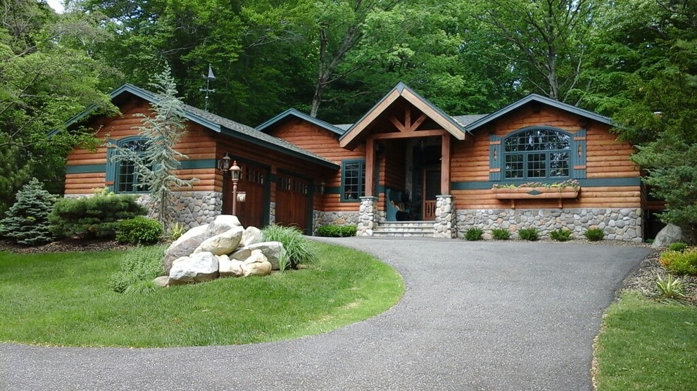 Cette photo montre une grande façade de maison marron montagne en bois de plain-pied avec un toit à croupette et un toit en shingle.