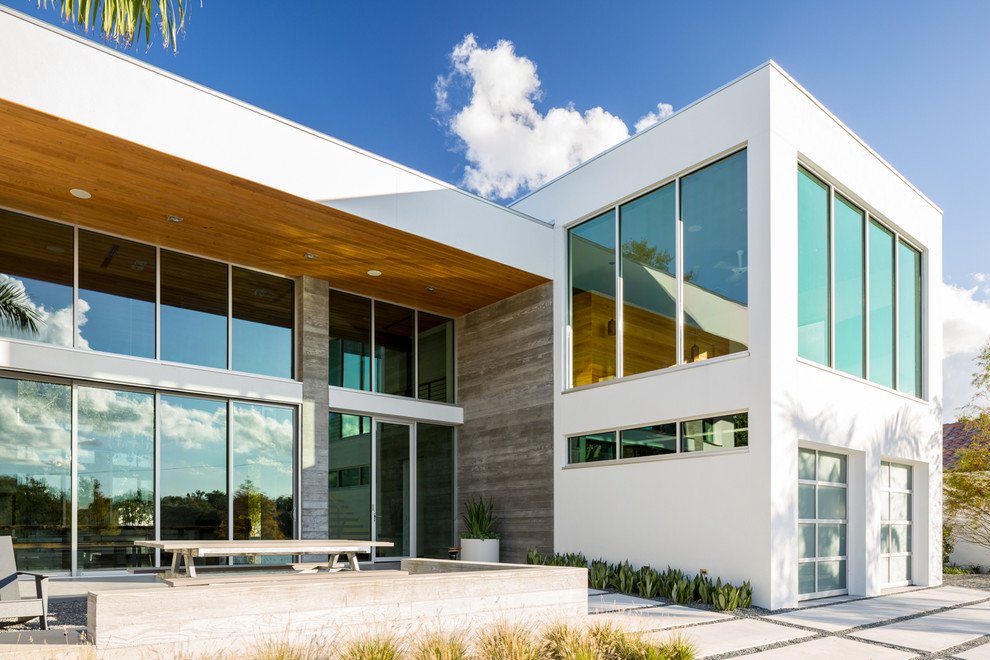 Diseño de fachada blanca moderna grande de dos plantas con revestimiento de hormigón y tejado plano