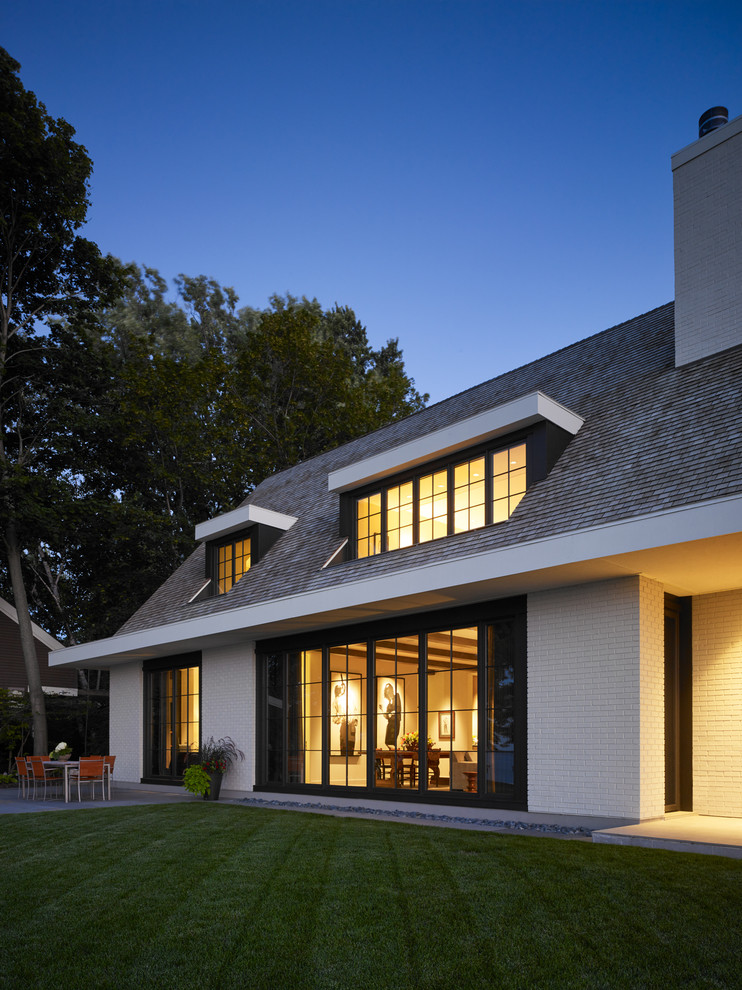 Réalisation d'une façade de maison blanche tradition en brique à un étage avec un toit à deux pans et un toit en shingle.