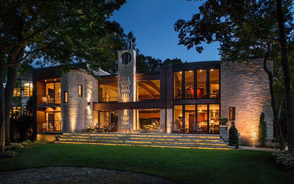 Стильный дизайн: двухэтажный, бежевый дом в стиле фьюжн с облицовкой из камня и односкатной крышей - последний тренд