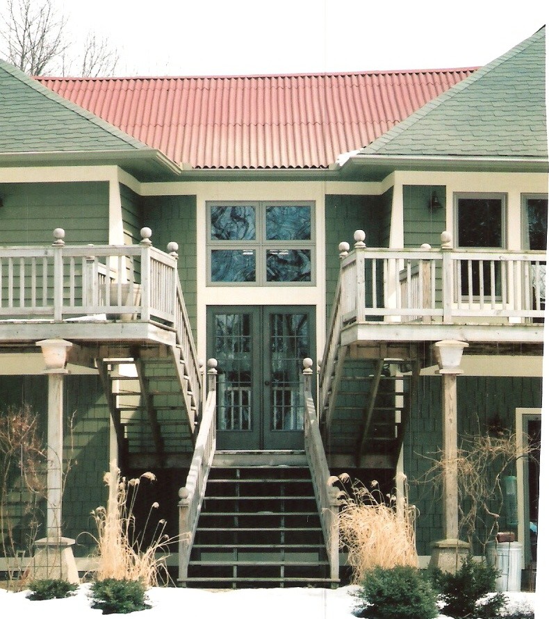 Cette photo montre une façade de maison verte éclectique en bois de taille moyenne et à un étage avec un toit à quatre pans.