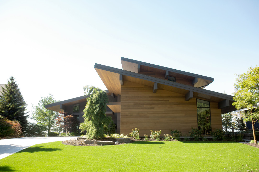 Пример оригинального дизайна: трехэтажный, коричневый частный загородный дом в современном стиле с комбинированной облицовкой и односкатной крышей