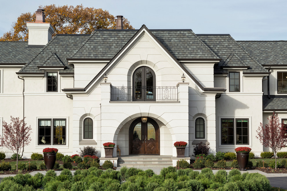 Foto della villa grande bianca classica a due piani con rivestimento in stucco, copertura a scandole e tetto a padiglione