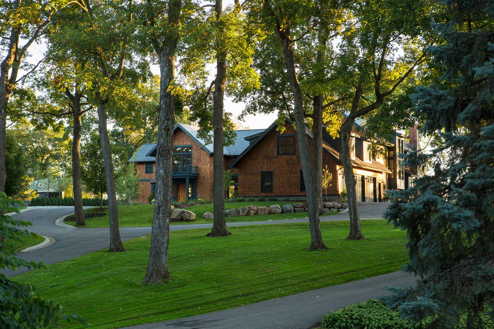 Esempio della villa ampia marrone american style a due piani con rivestimento in legno, tetto a capanna e copertura mista