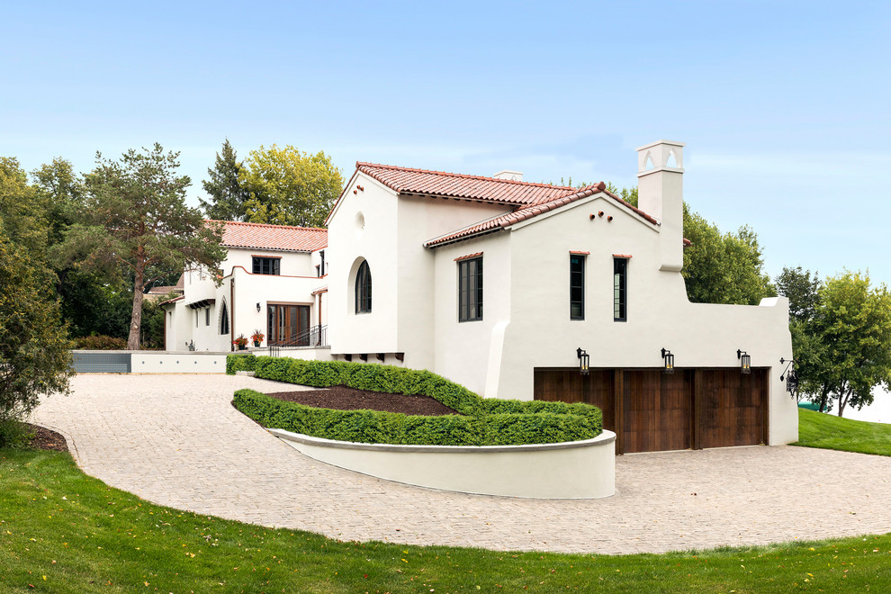 На фото: двухэтажный, белый частный загородный дом в средиземноморском стиле с двускатной крышей и черепичной крышей с