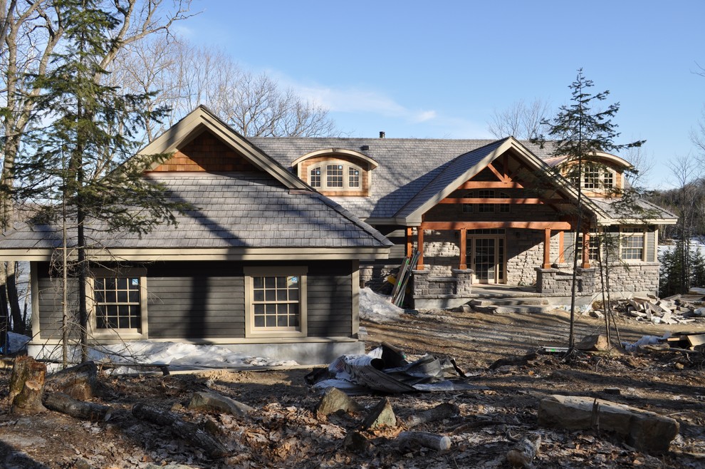 Cette photo montre une grande façade de maison grise tendance en pierre à un étage avec un toit à deux pans.