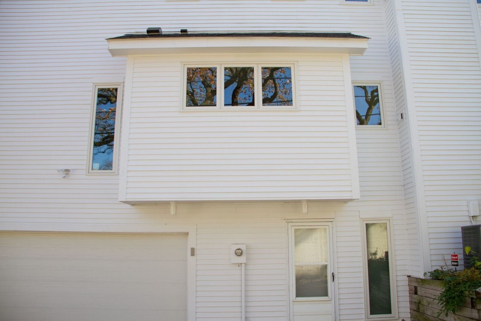 Foto della facciata di una casa grande bianca contemporanea a tre piani con rivestimento in legno e tetto a capanna