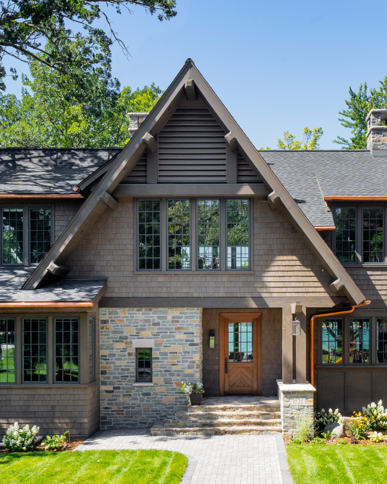 Imagen de fachada de casa marrón rústica de dos plantas con revestimientos combinados, tejado a dos aguas y tejado de teja de madera