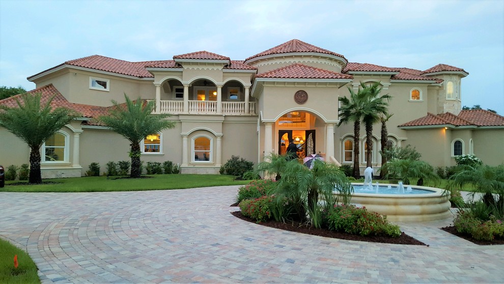 Expansive and beige mediterranean two floor render detached house in Tampa with a hip roof and a tiled roof.