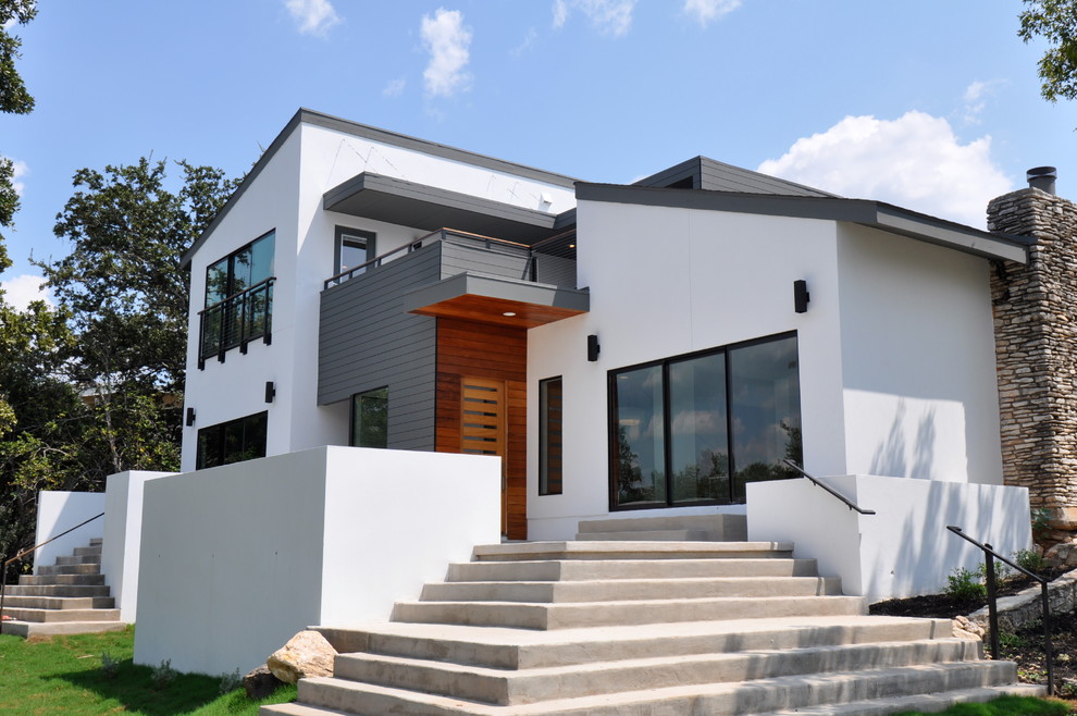 Aménagement d'une façade de maison blanche contemporaine en stuc de taille moyenne et à un étage avec un toit en appentis.