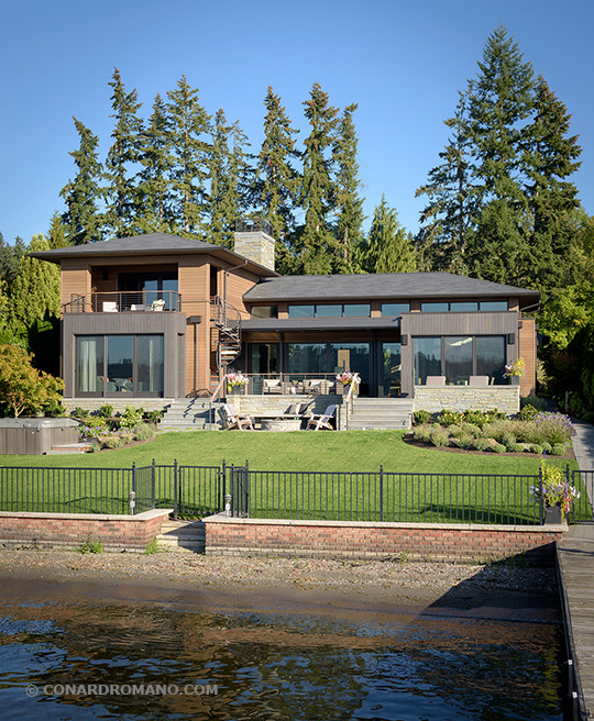 This is an example of a medium sized and brown contemporary two floor house exterior in Seattle with wood cladding and a hip roof.