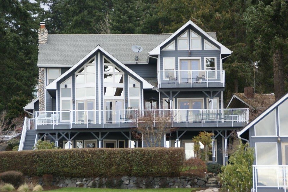 This is an example of an expansive and blue coastal detached house in Seattle with three floors, concrete fibreboard cladding, a pitched roof and a shingle roof.
