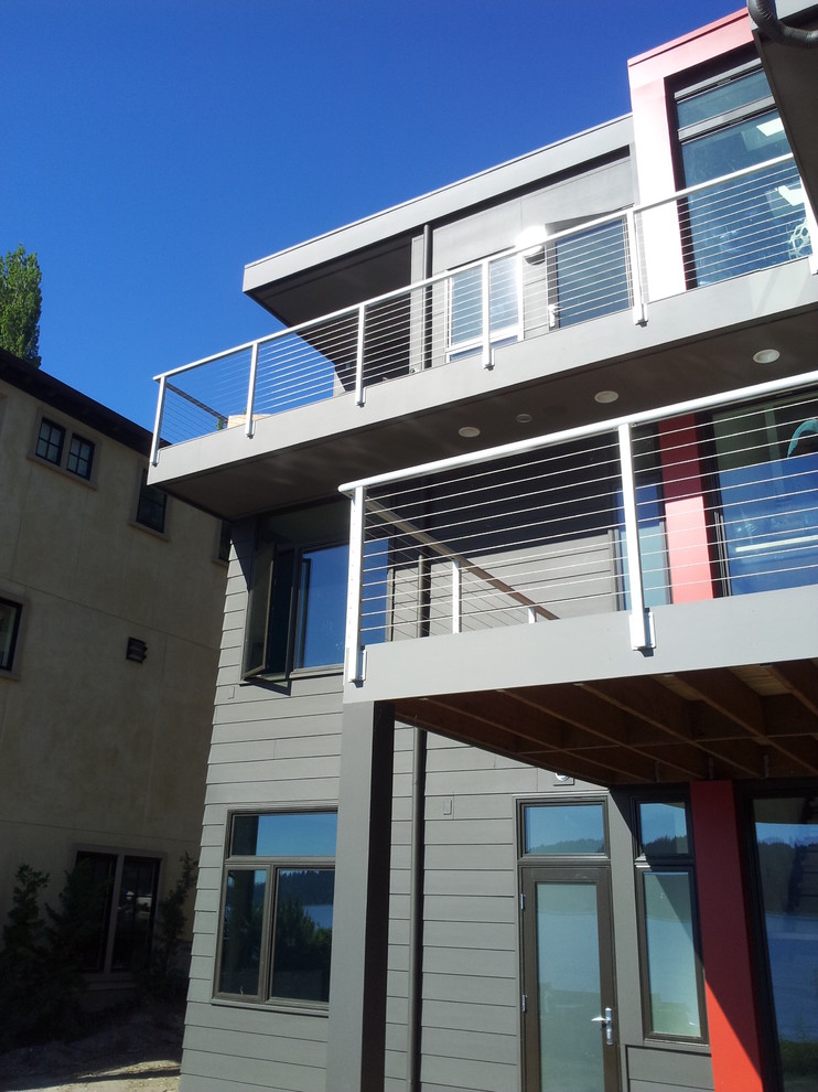 Réalisation d'une grande façade de maison grise design en panneau de béton fibré à deux étages et plus avec un toit plat.