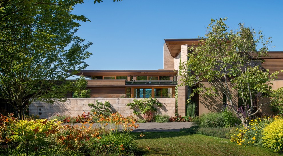 Cette image montre une très grande façade de maison marron design en bois à deux étages et plus avec un toit en appentis.